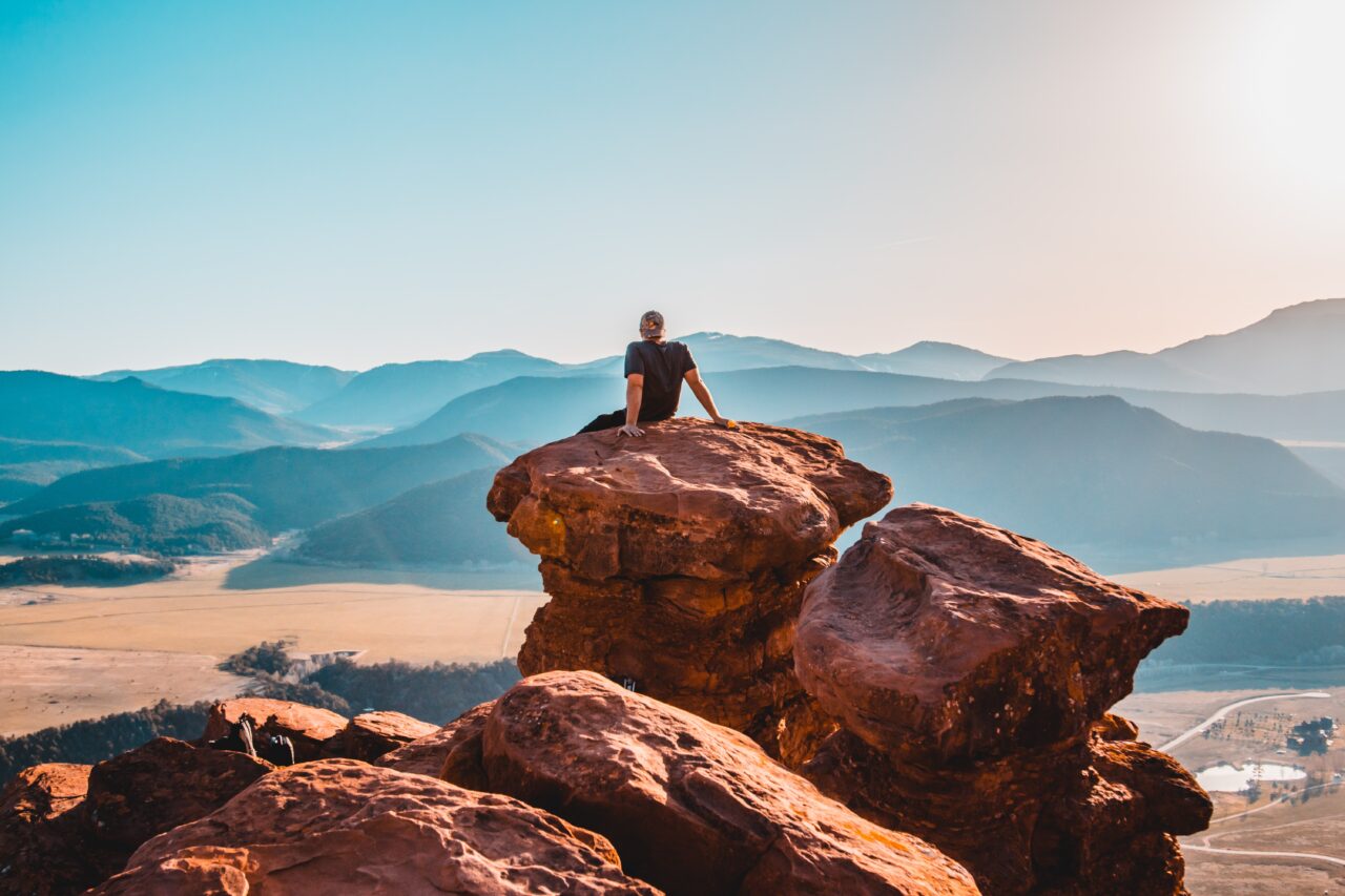 A person sits on the rocks thinking about improving CX with the help of hiking tips.