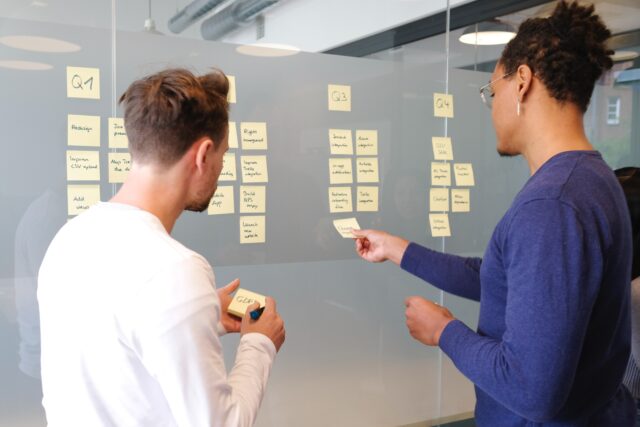 two persons looking at sticky notes while applying emotional intelligence in CX