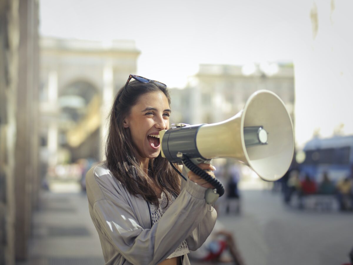 A woman holds a horn speaker as one of the Voice of the Customer tools.