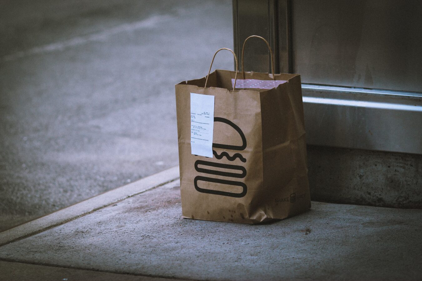 A bag with the hamburger illustration stands alone on the sidewalk and shows customer engagement is key to success because disengaged people are not inclined to buy stuff.