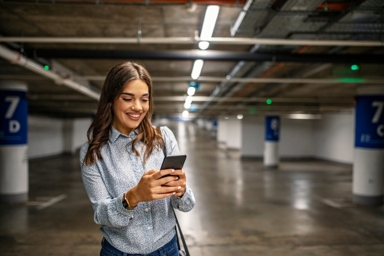 A woman looks at her phone while enjoying her parking experience.