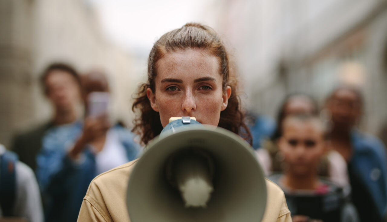 A woman speaks over a megaphone about a customer-focused revolution.