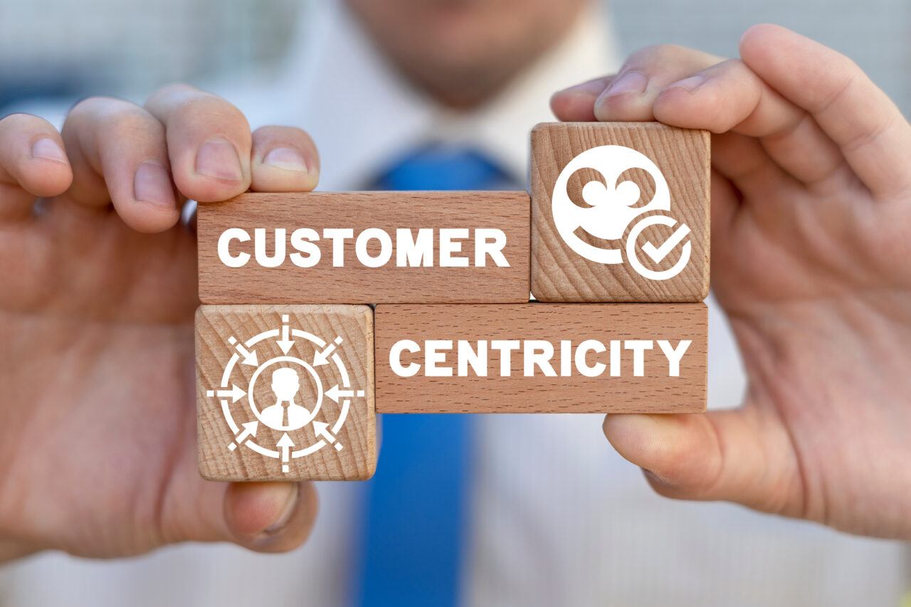 A person holds wooden blocks with customer-centricity written on them.