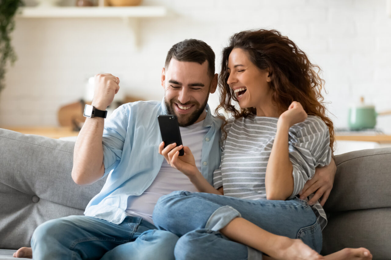 an image showing young couple being engaged and happy because they won an award playing an online purchasing game. 