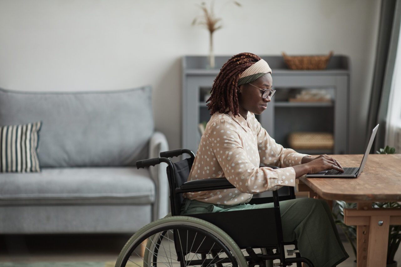 an image showing a black woman in wheels as she reads the 4 accessibility misconceptions. 