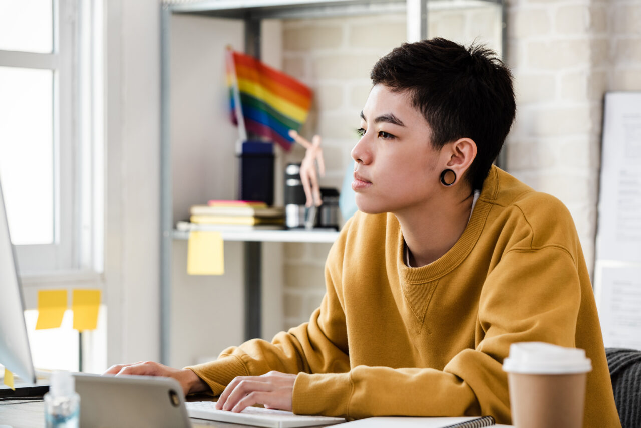 an image showing a transgender person sitting at the computer and creating more inclusive ads. 