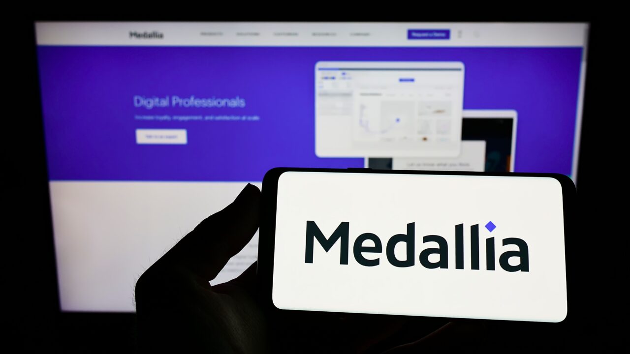 An image showing a person holding a phone with the Medallia logo on it. 