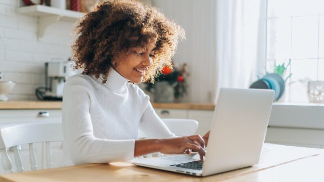 Dark skinned girl looks in laptop and enjoys online shopping