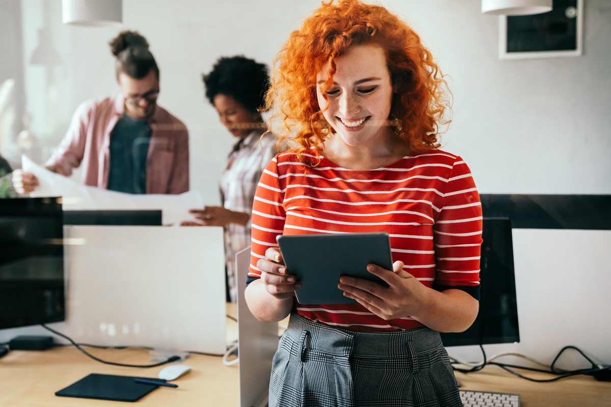 Diverse group of happy employees analyzing reports together, standing with papers, working together, discussing marketing, statistic data, talking, brainstorming. Business meeting concept