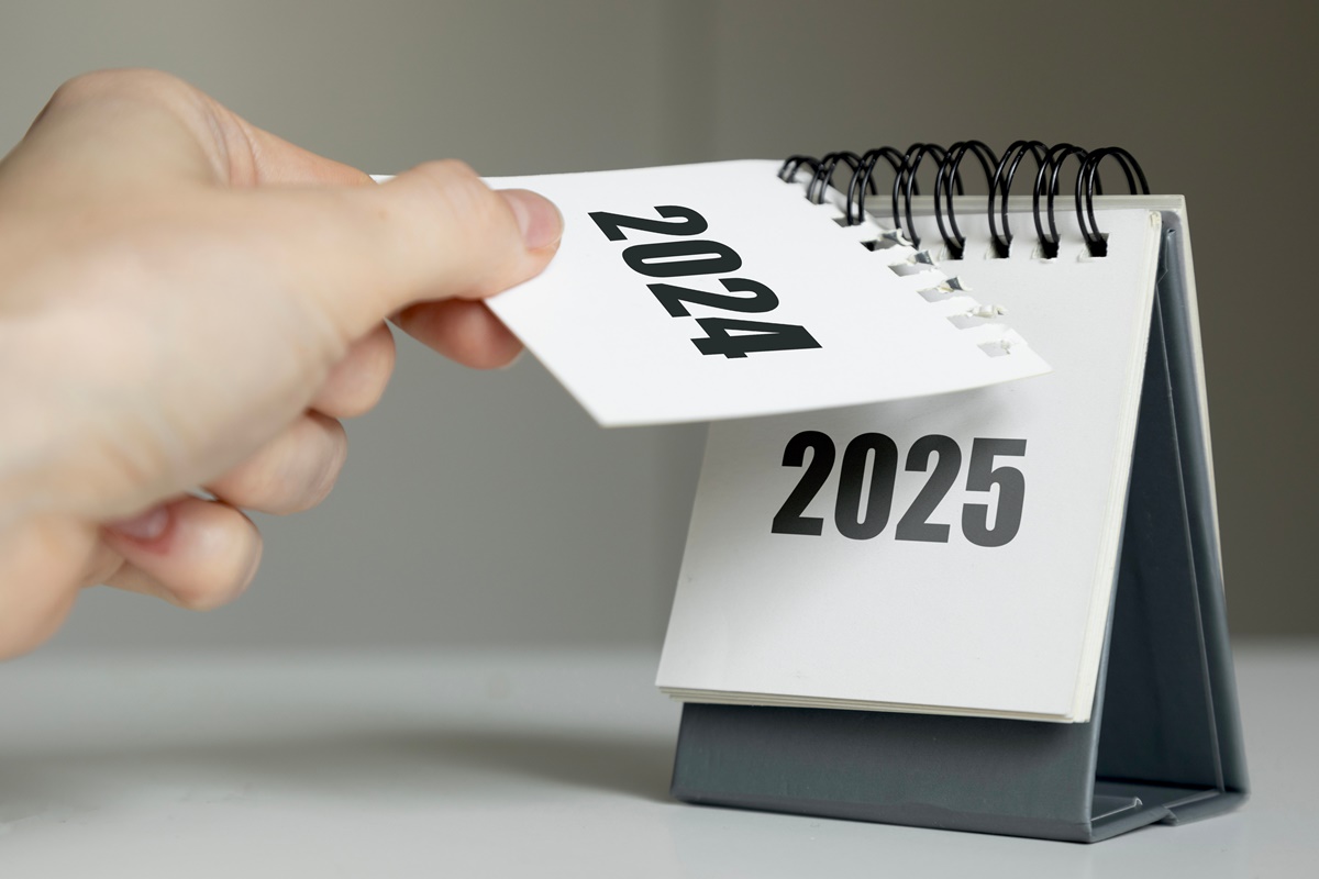 a woman's hand turns over a calendar sheet. year change from 2024 to 2025.