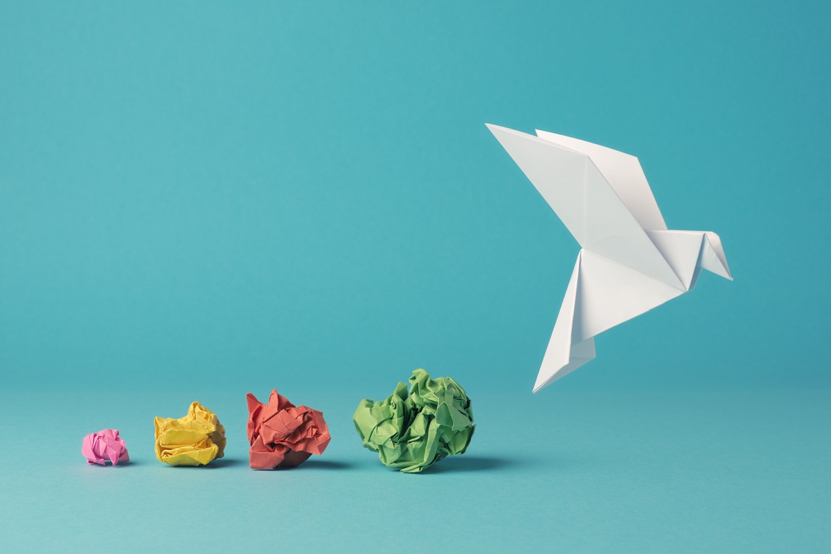 Colorful crumpled paper balls with an origami paper dove, peace, freedom, diversity or opportunity concept on a blue background