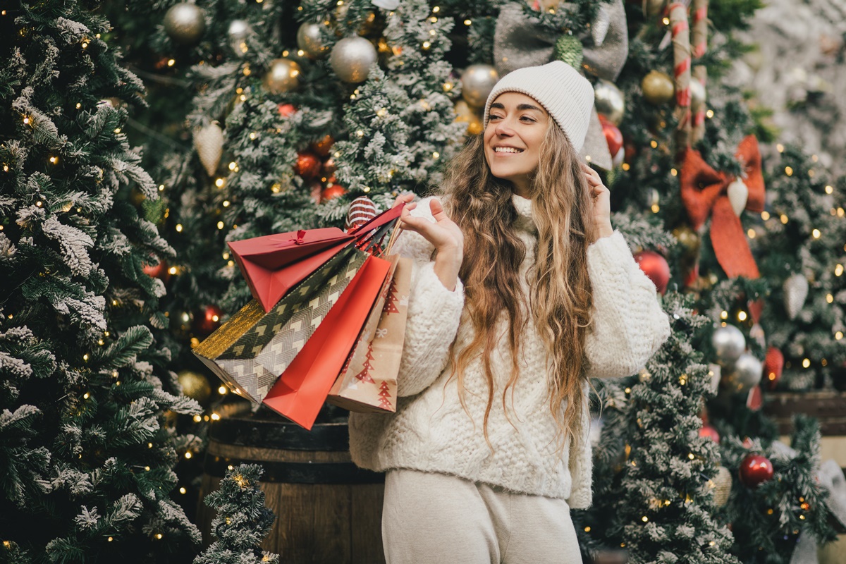 Young beautiful happy womam enjoying Christmas shopping on a decorated street.