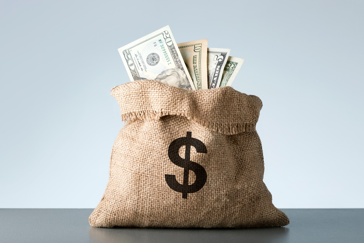 Burlap with dollar banknotes on gray background. Bribe or bonus concept.