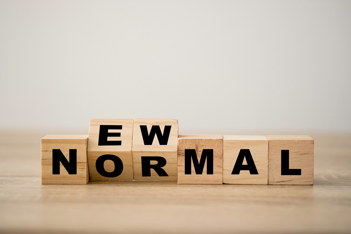 Hand flipping wooden block cubes for new normal wording. The world is changing to balance it into new normal include business , economy , environment and health.